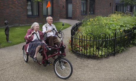 dementia village cc ouple on tricycle