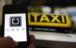 File illustration picture showing the logo of car-sharing service app Uber on a smartphone next to the picture of an official German taxi sign